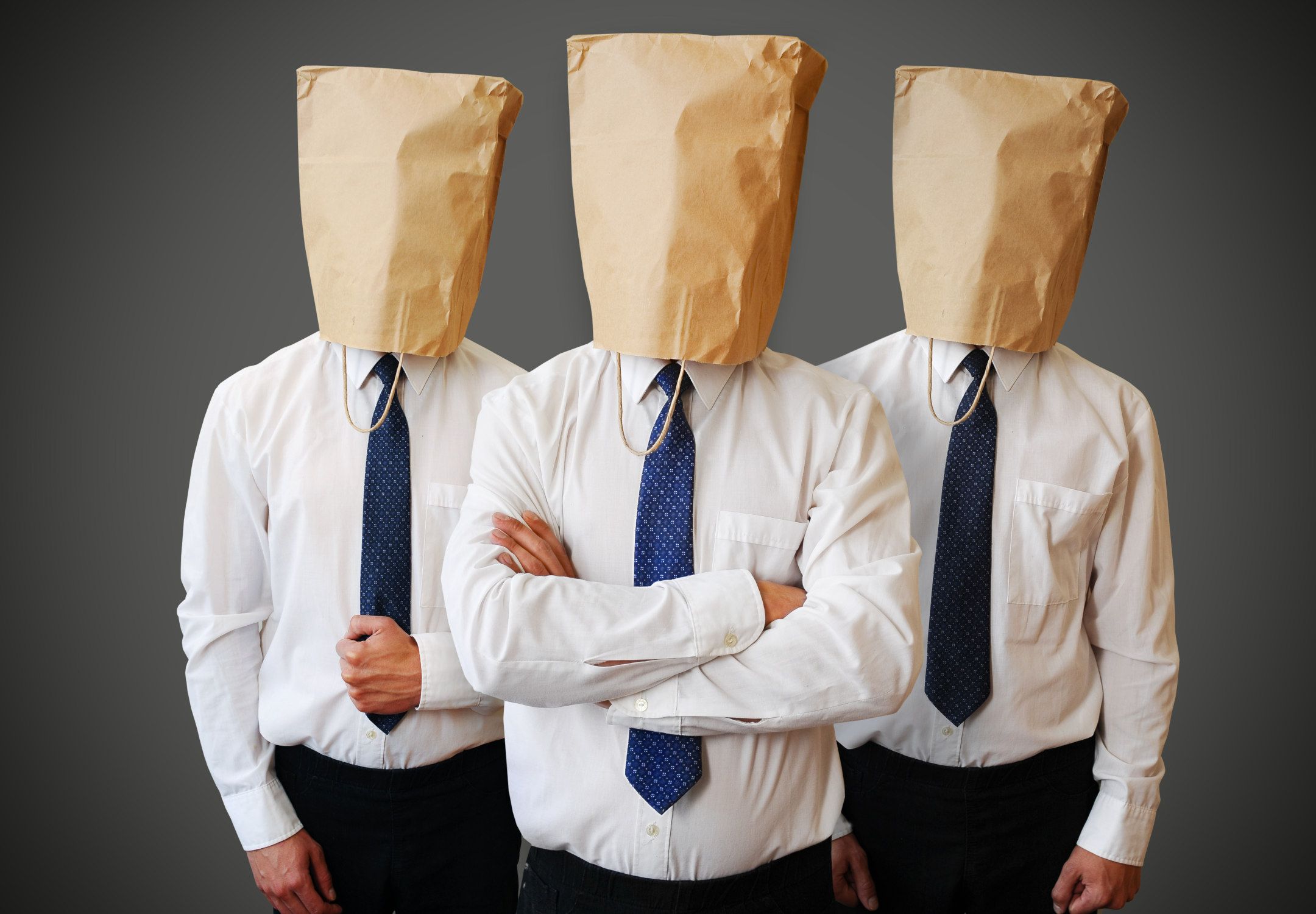 Opstillet foto, hvor tre personer iført slips har maskeret sig med hver sin papirspose over hovedet