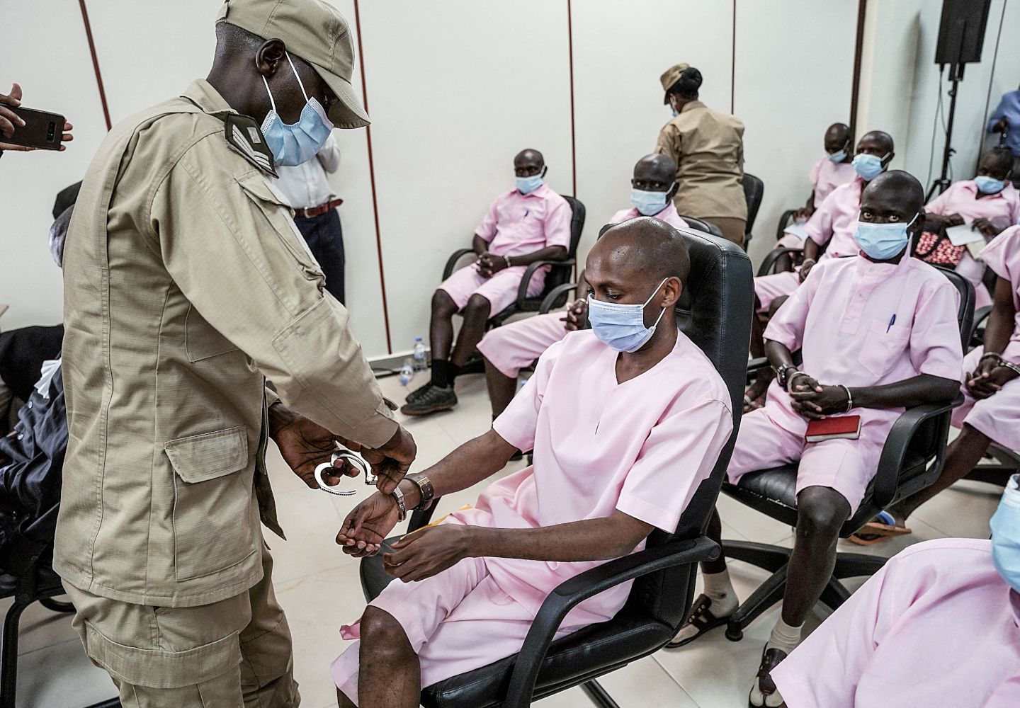 Foto af en fængselsvagt, der fjerner håndjernene fra en af de dømte i en terrorsag ført ved Rwandas højesteret