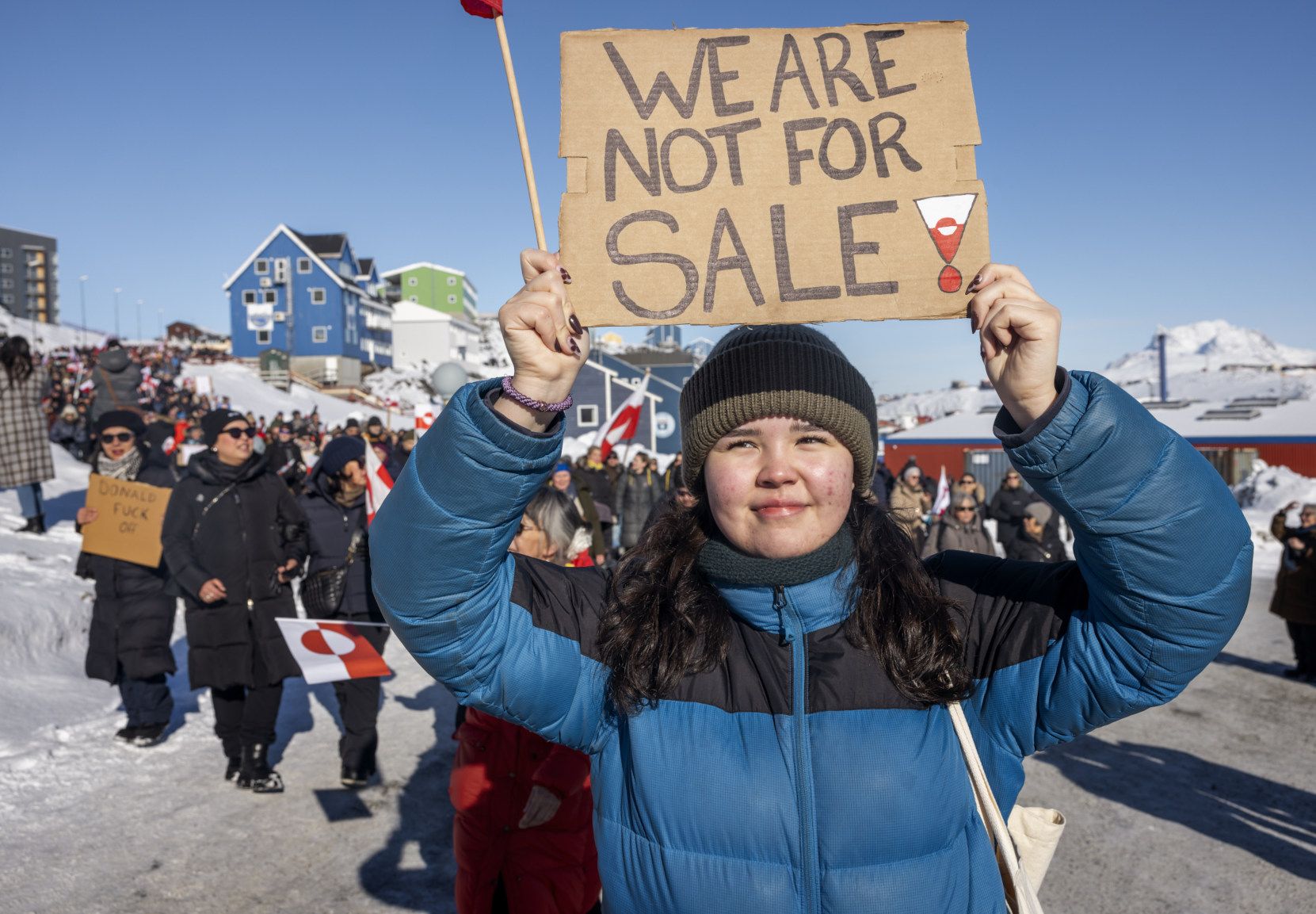 Foto fra en USA-kritisk demonstration i Nuuk. Forrest ses en kvinde med et skilt, hvorpå der står "We are not for sale"