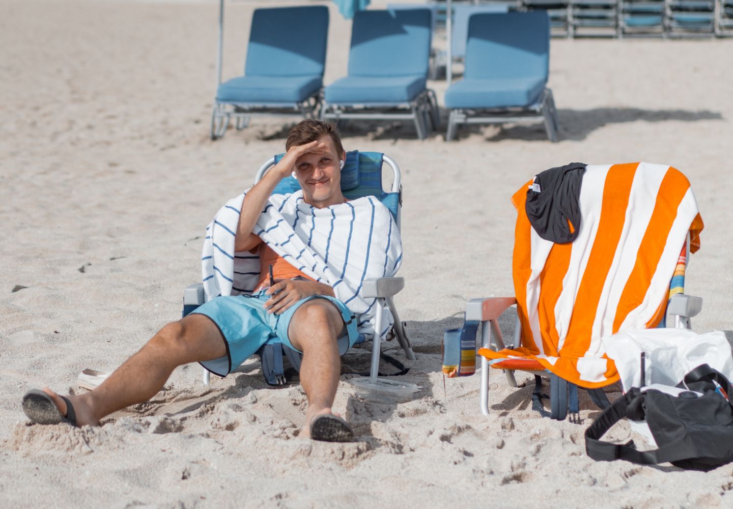 Foto af ung mand i en strandstol på en sandstrand