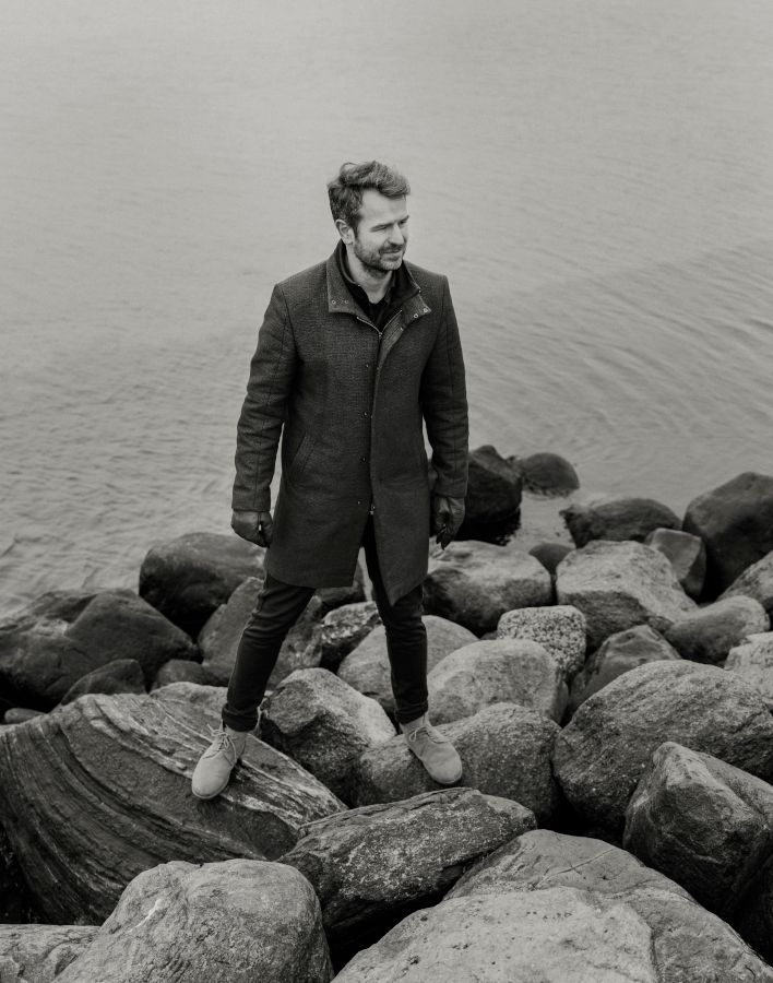Foto af Jesper H. Bertelsen, der står på et stendige nær havet