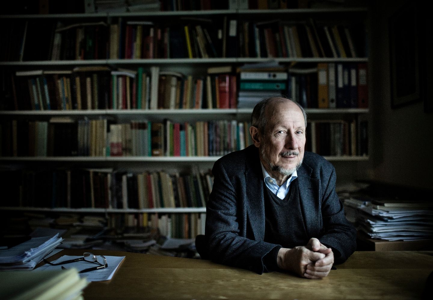 Niels Kærgård sidder ved sit skrivebord med en fyldt bogreol i baggrunden.