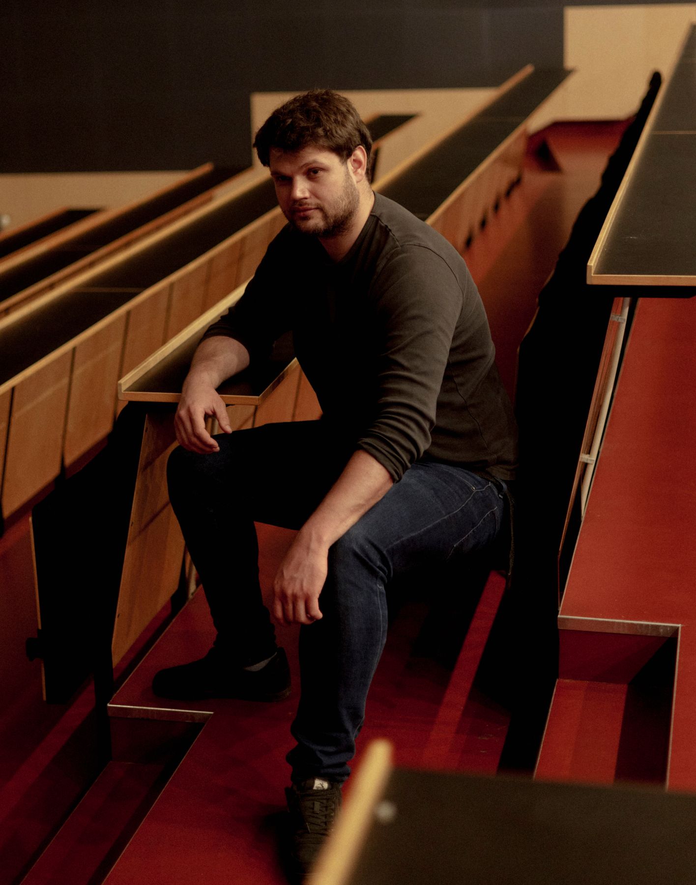 Portrætfoto af Christian Ramon, der sidder i et auditorium