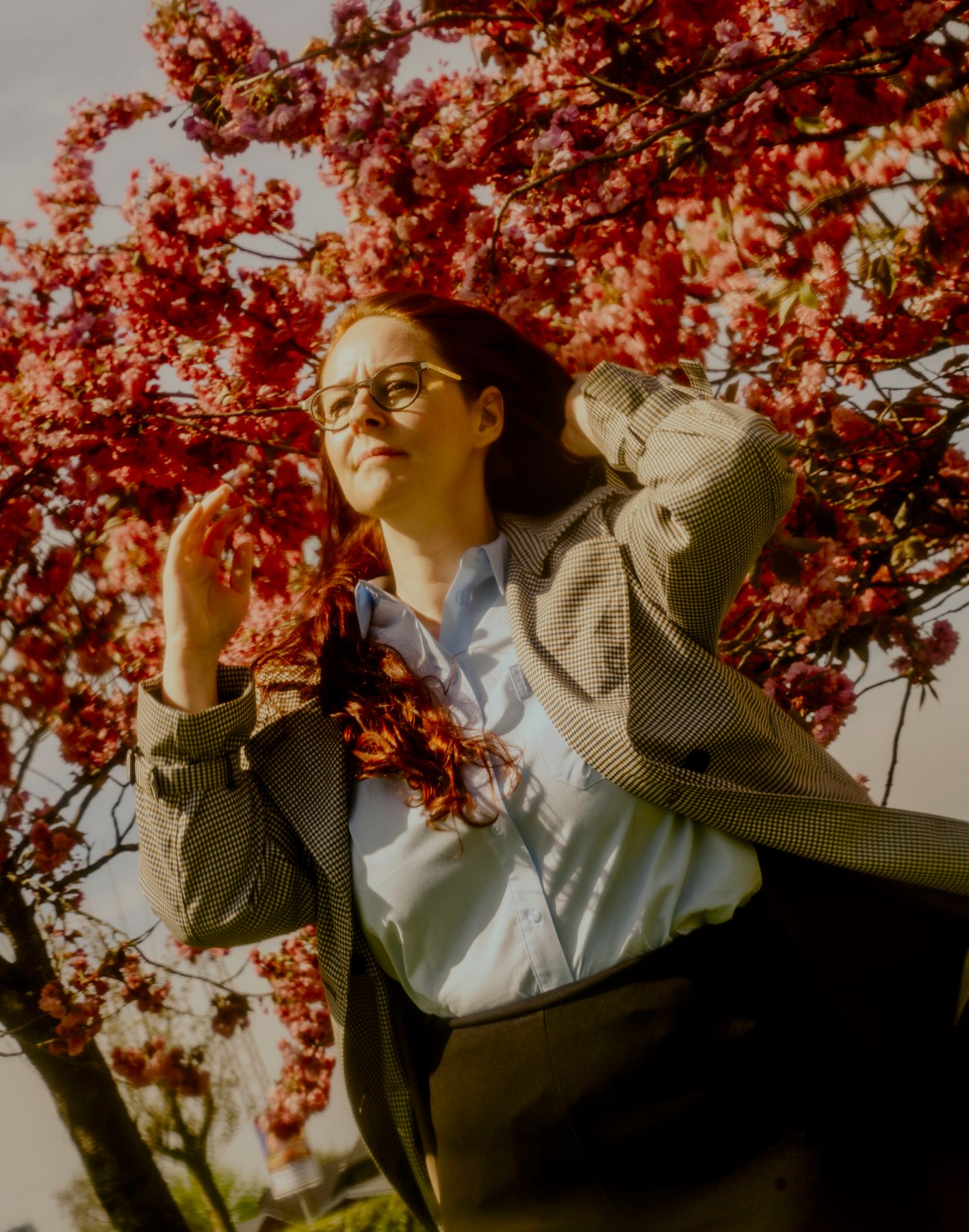 Portrætfoto af Helle Malmberg Amstrup med et træs rødlige blomsterflor i baggrunden