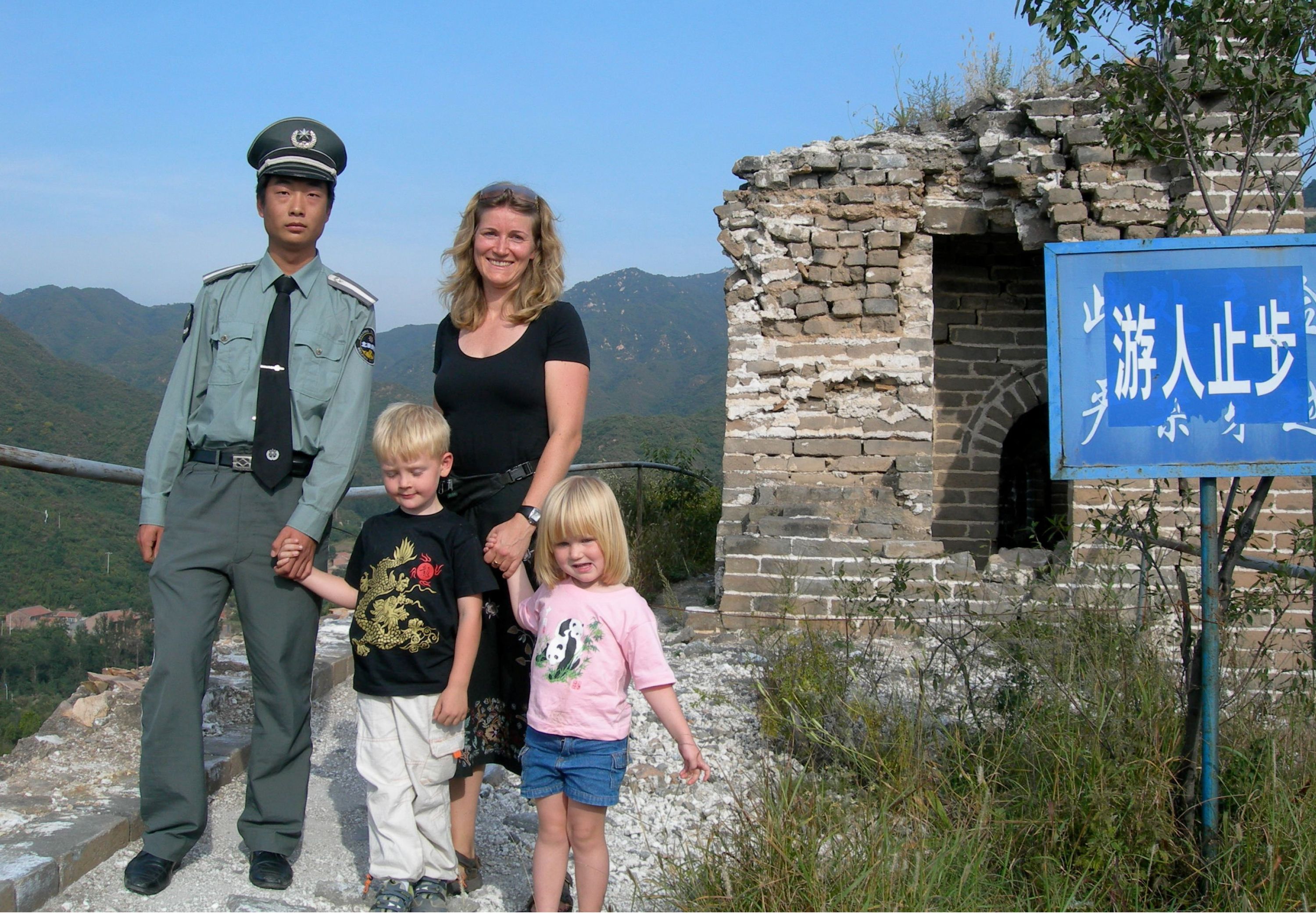 Foto af Mette Ehlers og to af hendes børn sammen med en kinesisk embedsmand i uniform