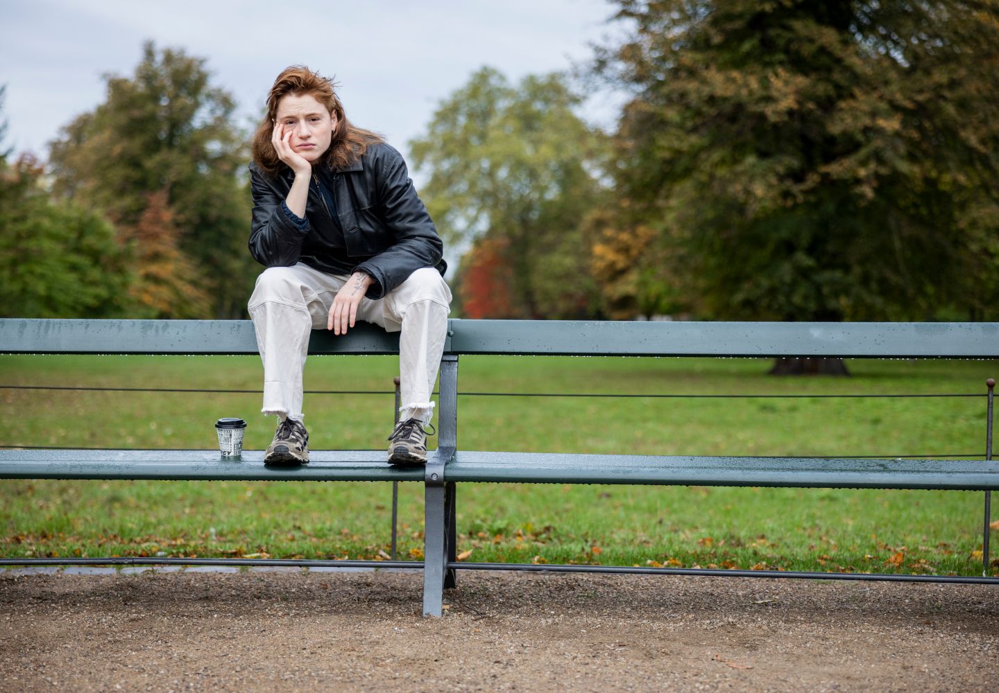 Foto af Nina Rask, der sidder på ryglænet af en parkbænk med hånden under hagen
