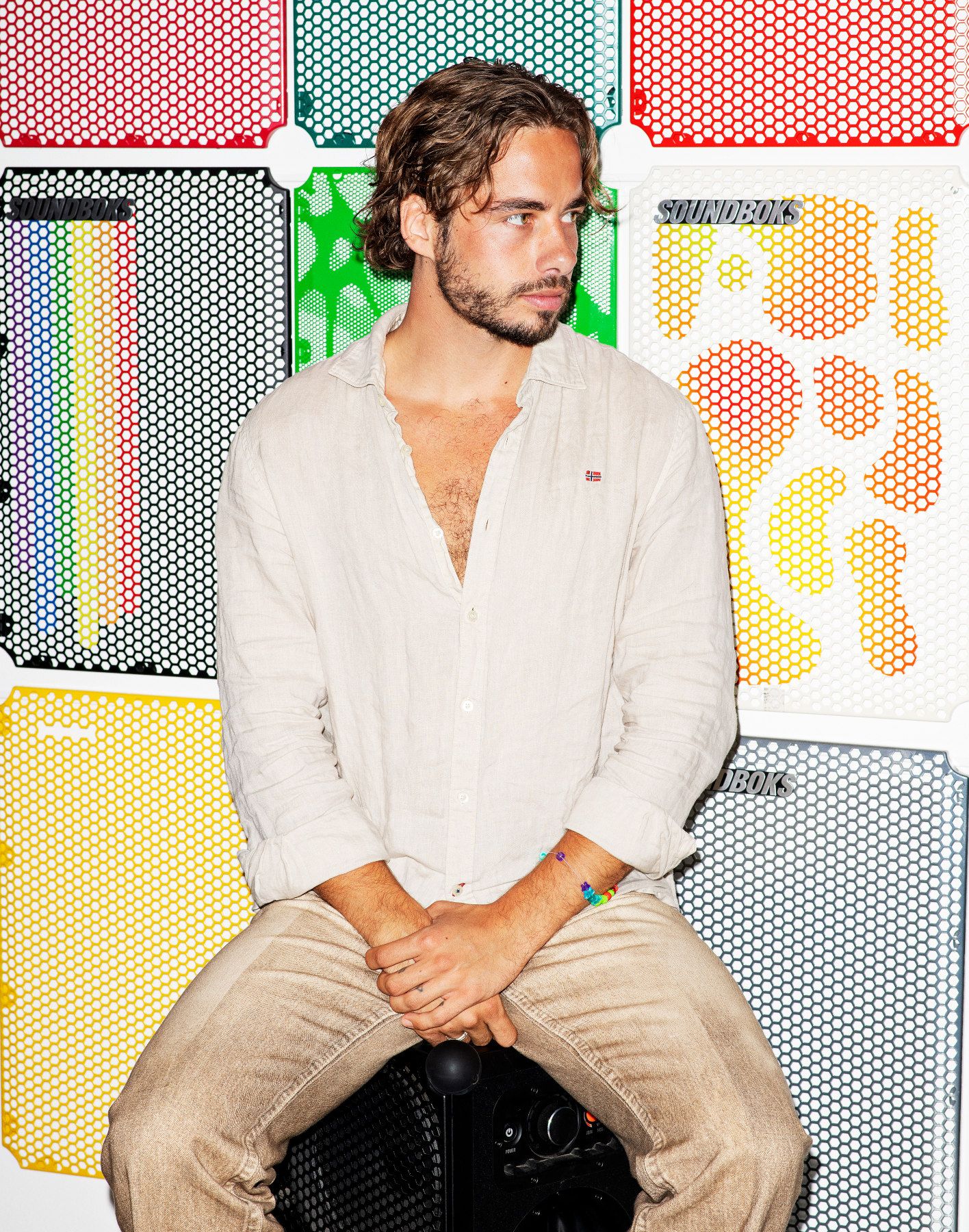 Foto af Jesper Theil Thomsen siddende på en Soundboks foran en farverig baggrund
